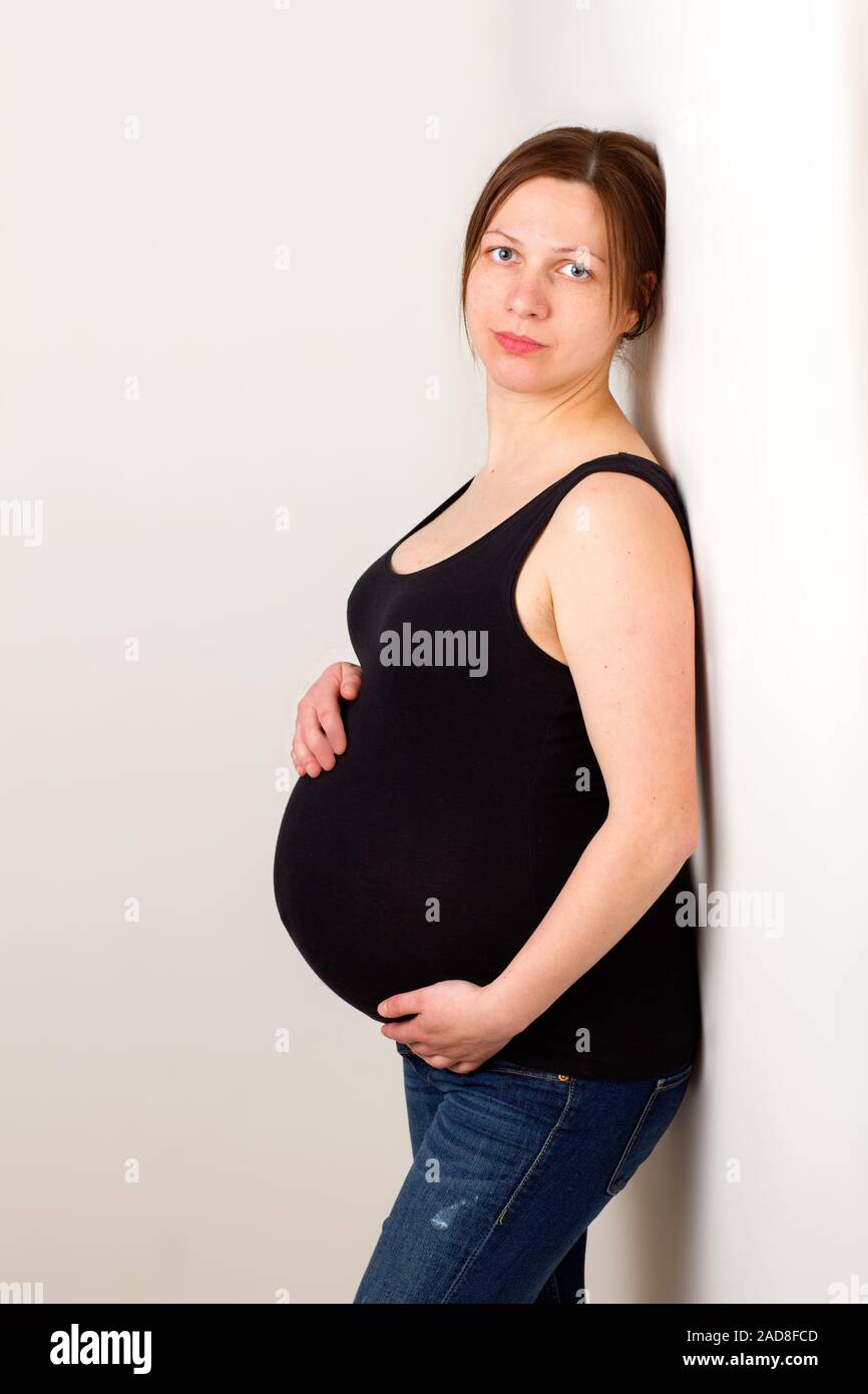 Young pregnant woman, expectant mother on white background, close-up of pregnant belly Stock Photo