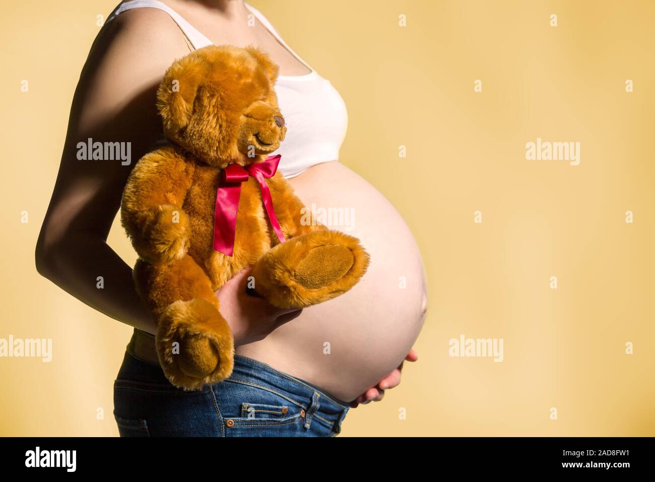 pregnant woman, expectant mother on yellow background, close-up of pregnant belly Stock Photo