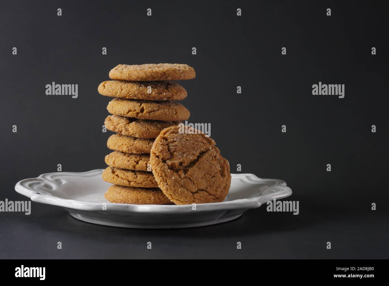 A stack of chewy ginger cookies on a white plate and a black background; copy space Stock Photo