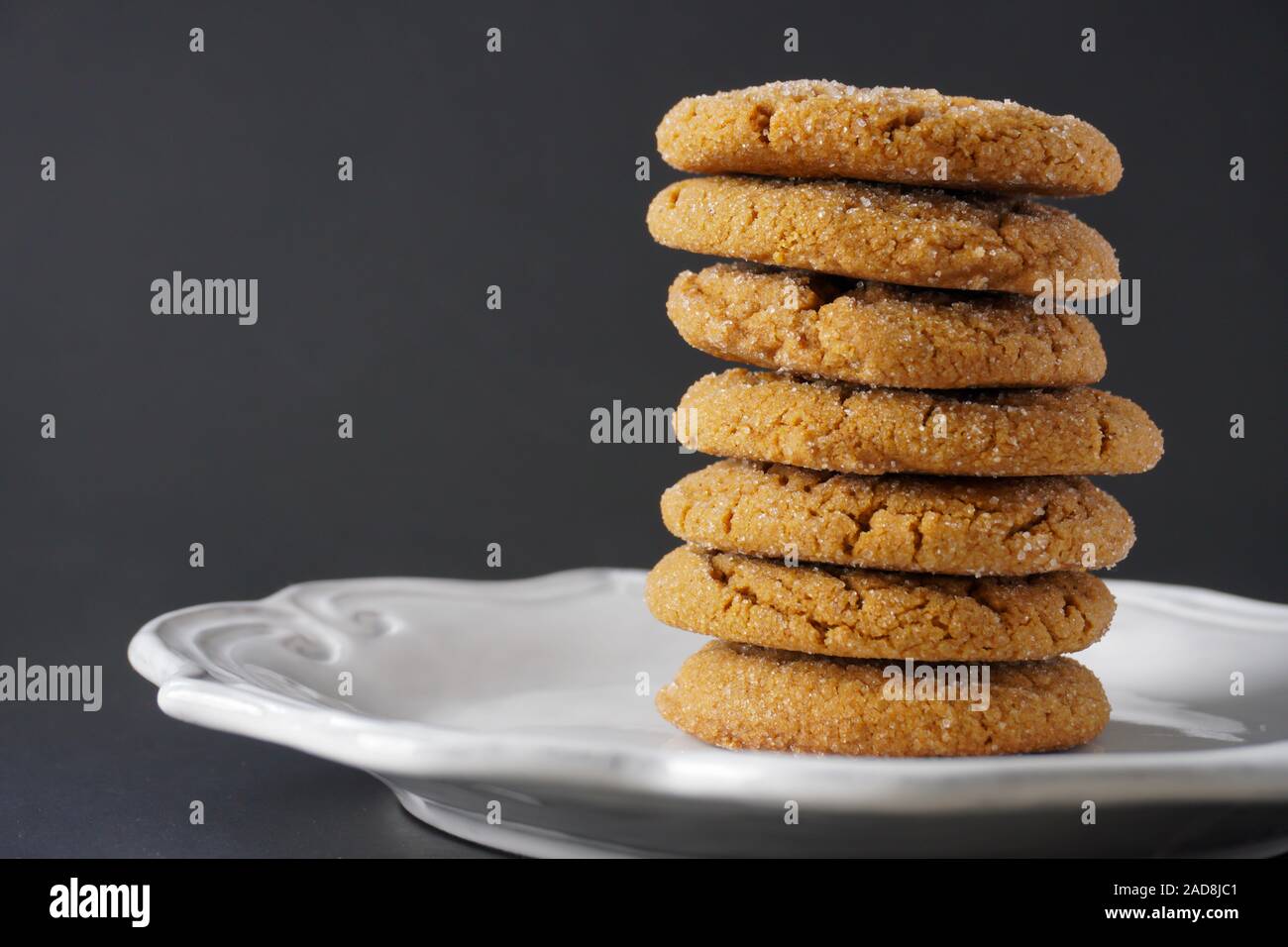 Close-up image of a stack of ginger Christmas cookies on a white plate with a black background; copy space Stock Photo