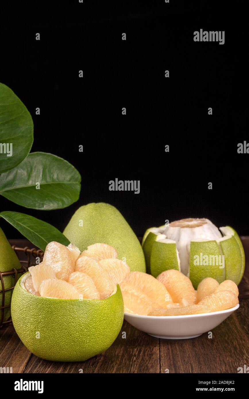 Fresh peeled pomelo, grapefruit, shaddock with green leaves on dark