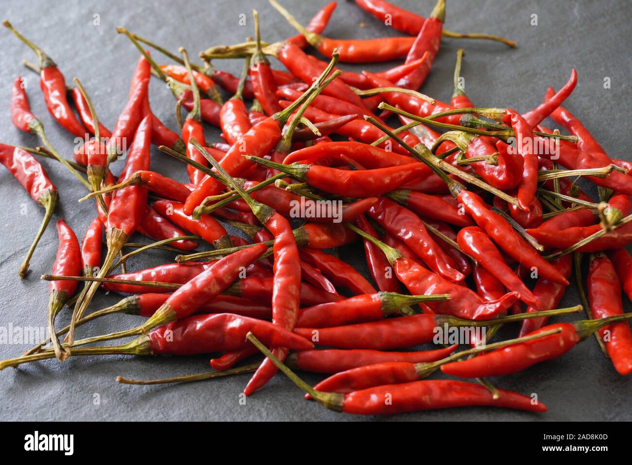 Close-up image of a pile of hot Thai bird chiles on a gray slate background; landscape view Stock Photo