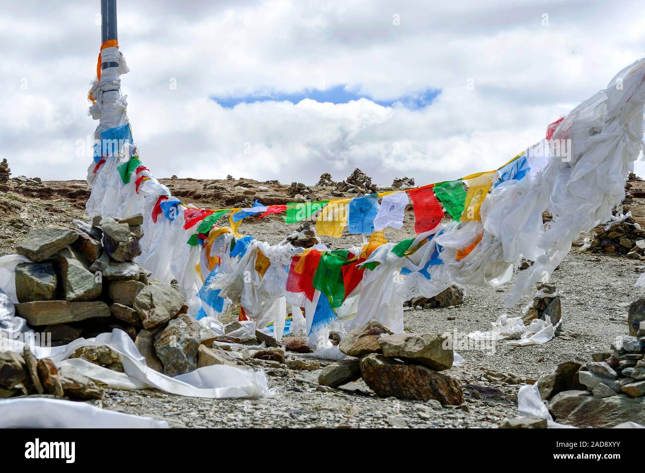 Lung ta prayer flags, white scarves (khatas) and cairns flank the border of a Chinese military zone in Brahmaputra Valley in Tibet Autonomous Region. Stock Photo