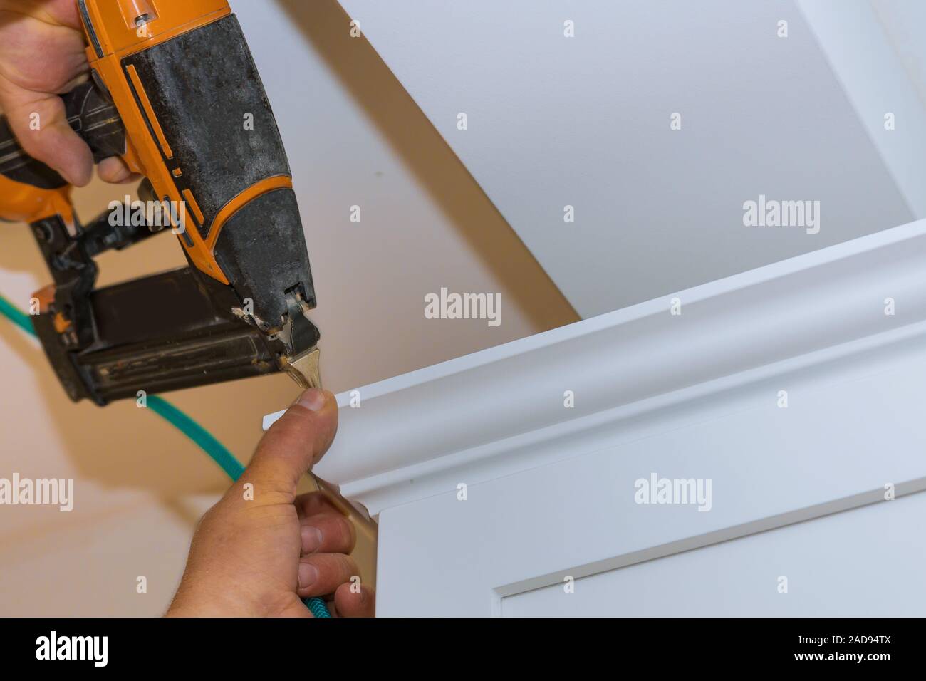 Air nailer tool close up of carpenter using nail gun to crown moldings