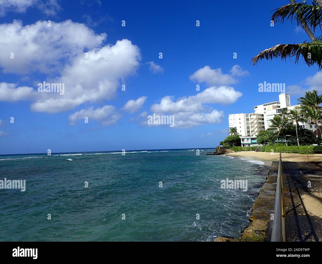 Path to Makalei Beach with waves lapping, napakaa, lava rock wall and Coconut trees along the shore on a wonderful day in Oahu, Hawaii. Stock Photo