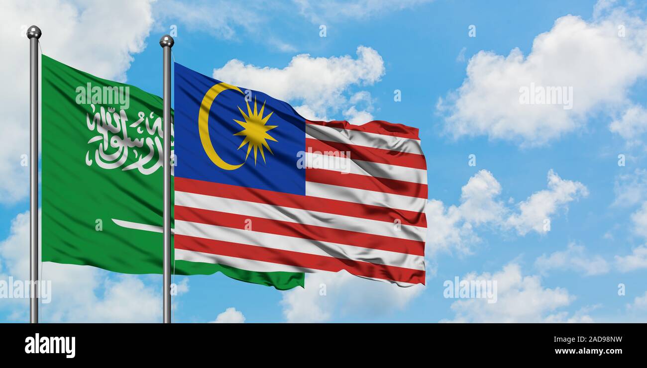 Saudi Arabia and Malaysia flag waving in the wind against white cloudy blue sky together. Diplomacy concept, international relations. Stock Photo
