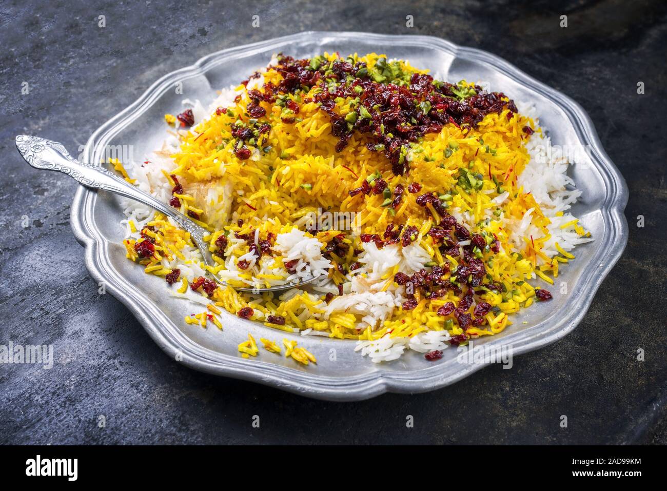 Traditional Iranian steamed saffron rice with berberis and pistachios as closeup on a pewter plate Stock Photo