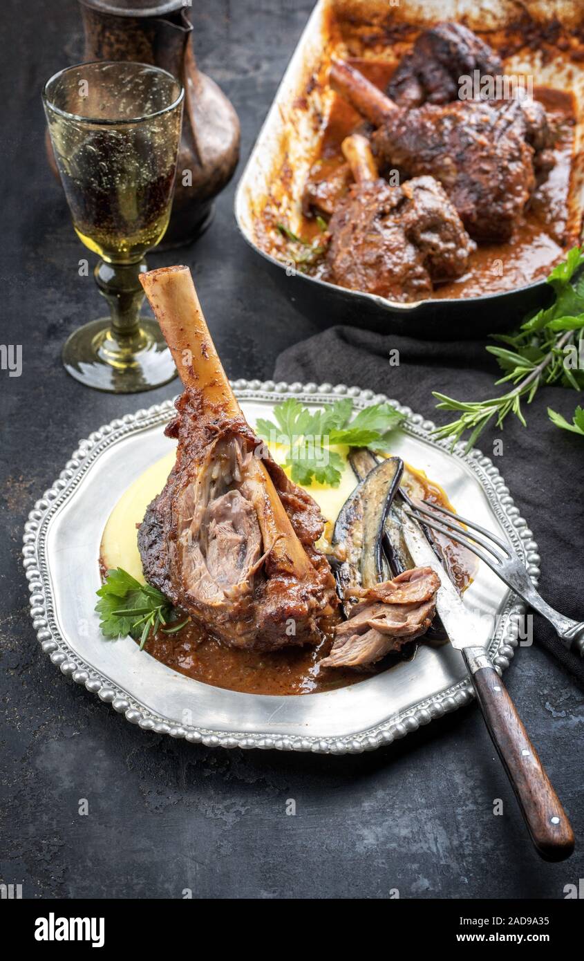 Traditional barbecue leg of lamb with eggplants and mashed potatoes in tomato red wine sauce as
