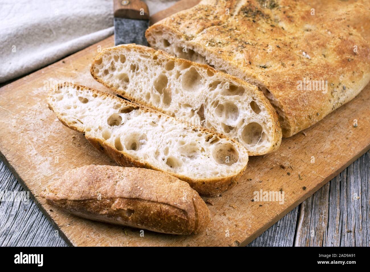 Traditional Italian ciabatta bread with herbs as closeup on a cutting board Stock Photo
