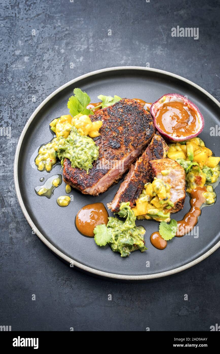 Traditional exotically blackened Cajun style tuna fish fillet with mango avocado salad Stock Photo