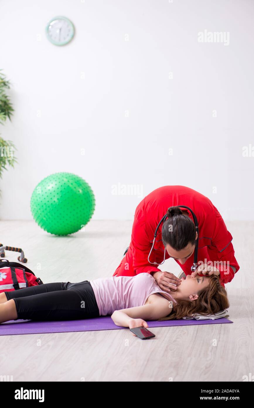 Paramedic in red visiting young woman in gym Stock Photo