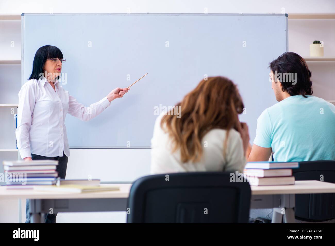 Old female english teacher and students in the classroom Stock Photo