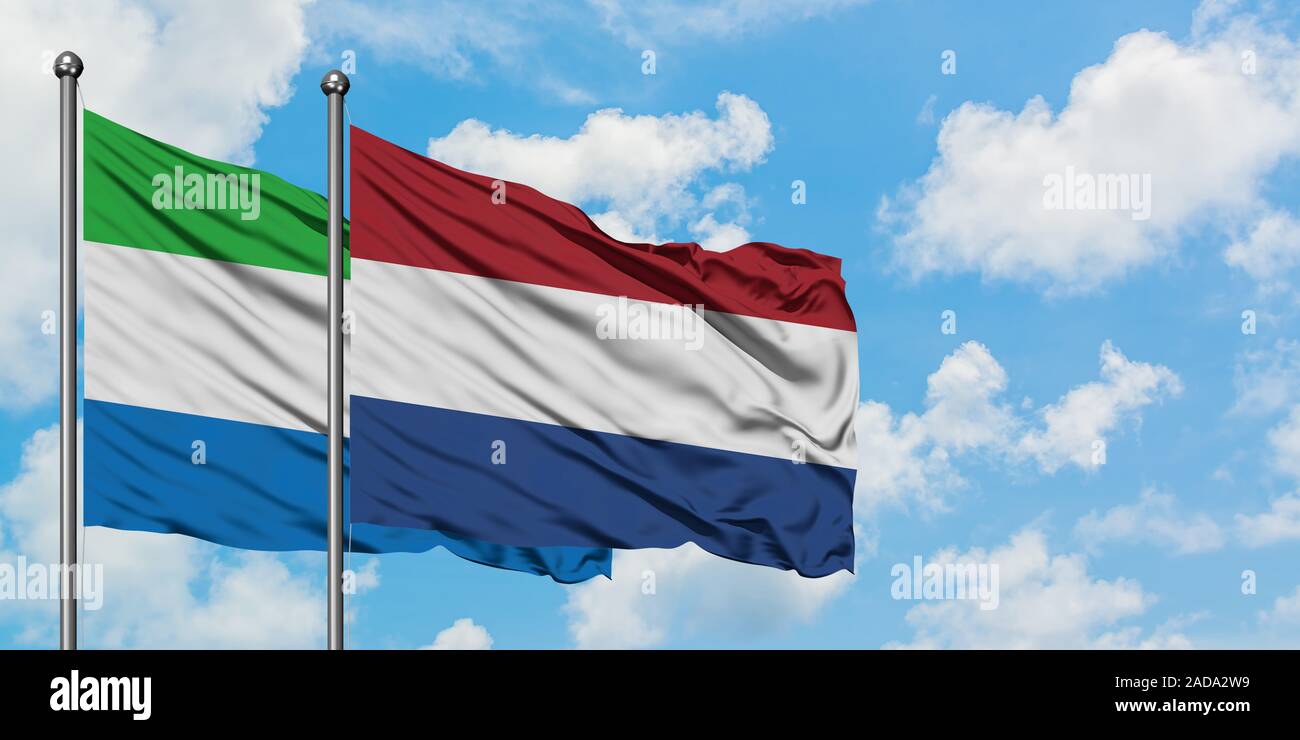 Sierra Leone and Netherlands flag waving in the wind against white cloudy blue sky together. Diplomacy concept, international relations. Stock Photo