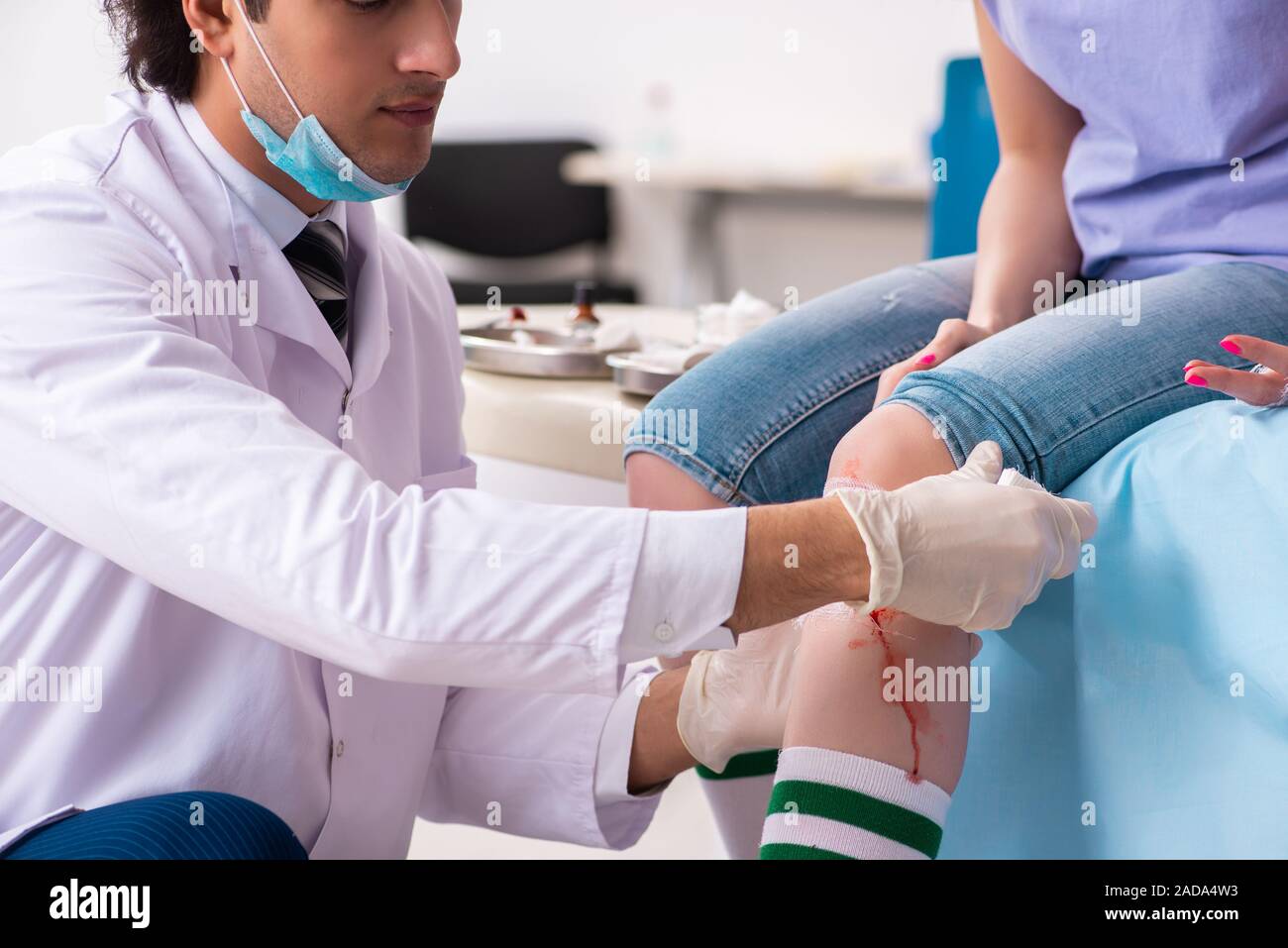 Leg injured young woman visiting male doctor Stock Photo