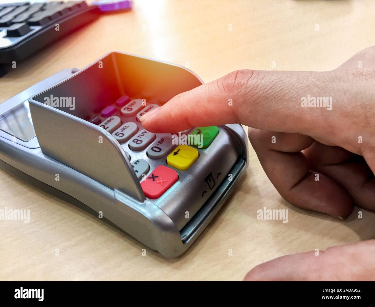 Credit card payment. Finger pointing to the number button on payment machine  without card on wooden table Stock Photo - Alamy