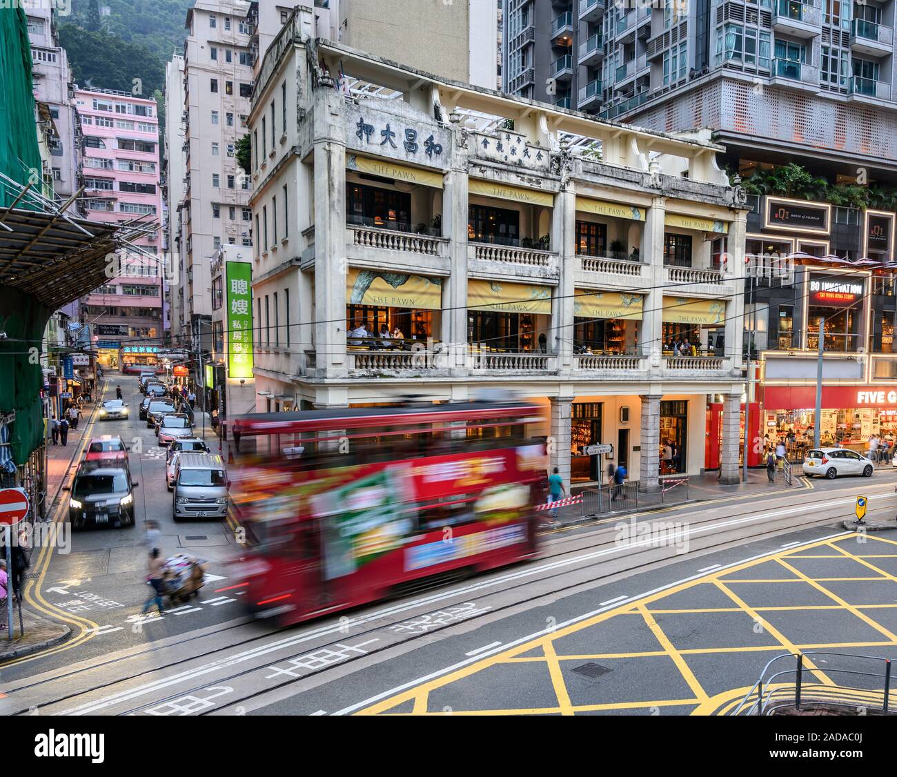 A tram passes by The Pawn Building in Wan Chai Hong Kong. The Pawn is a restored colonial era building originally housing a pawn shop. Stock Photo