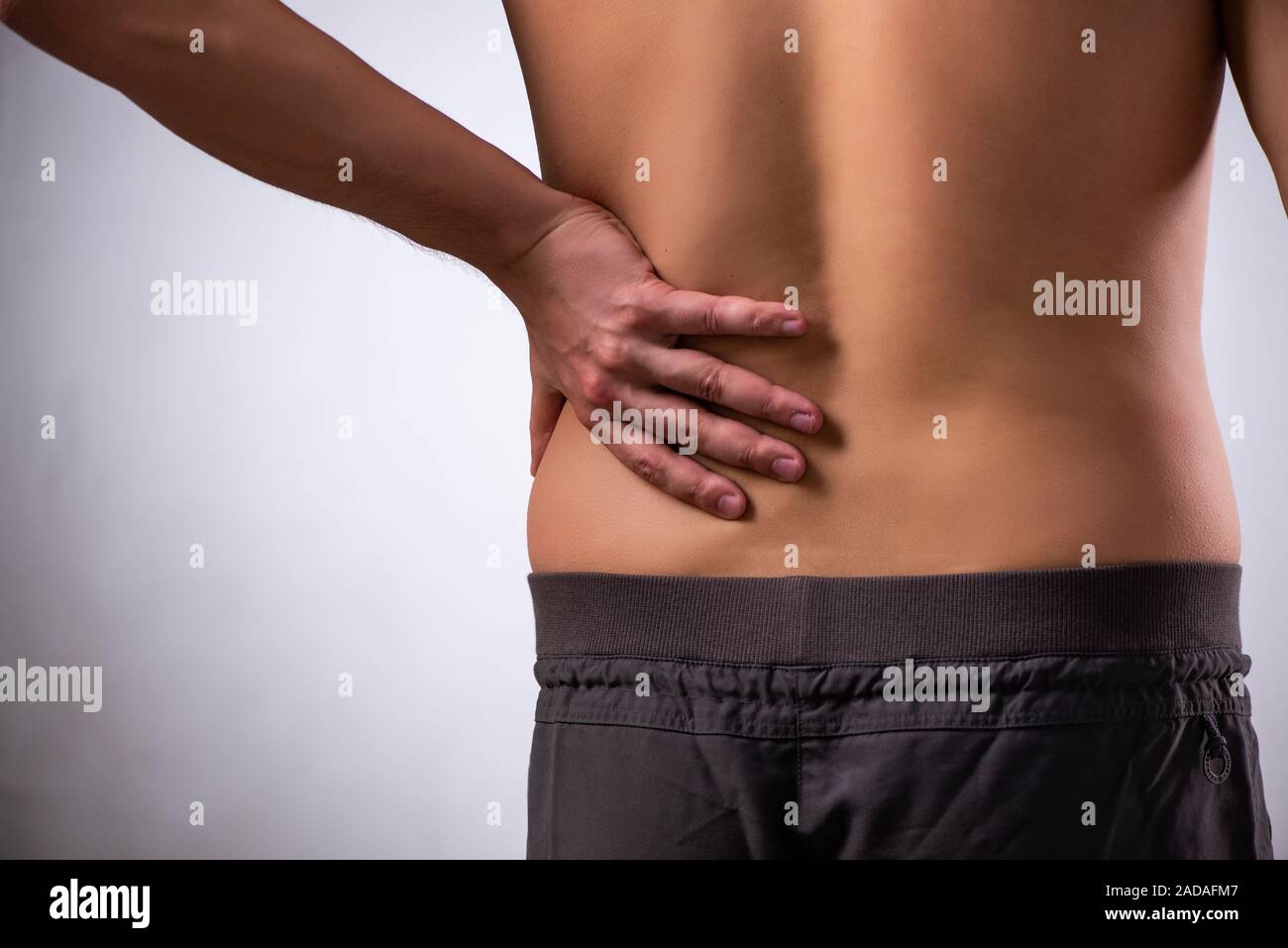 Man suffering from backbain on gray Stock Photo