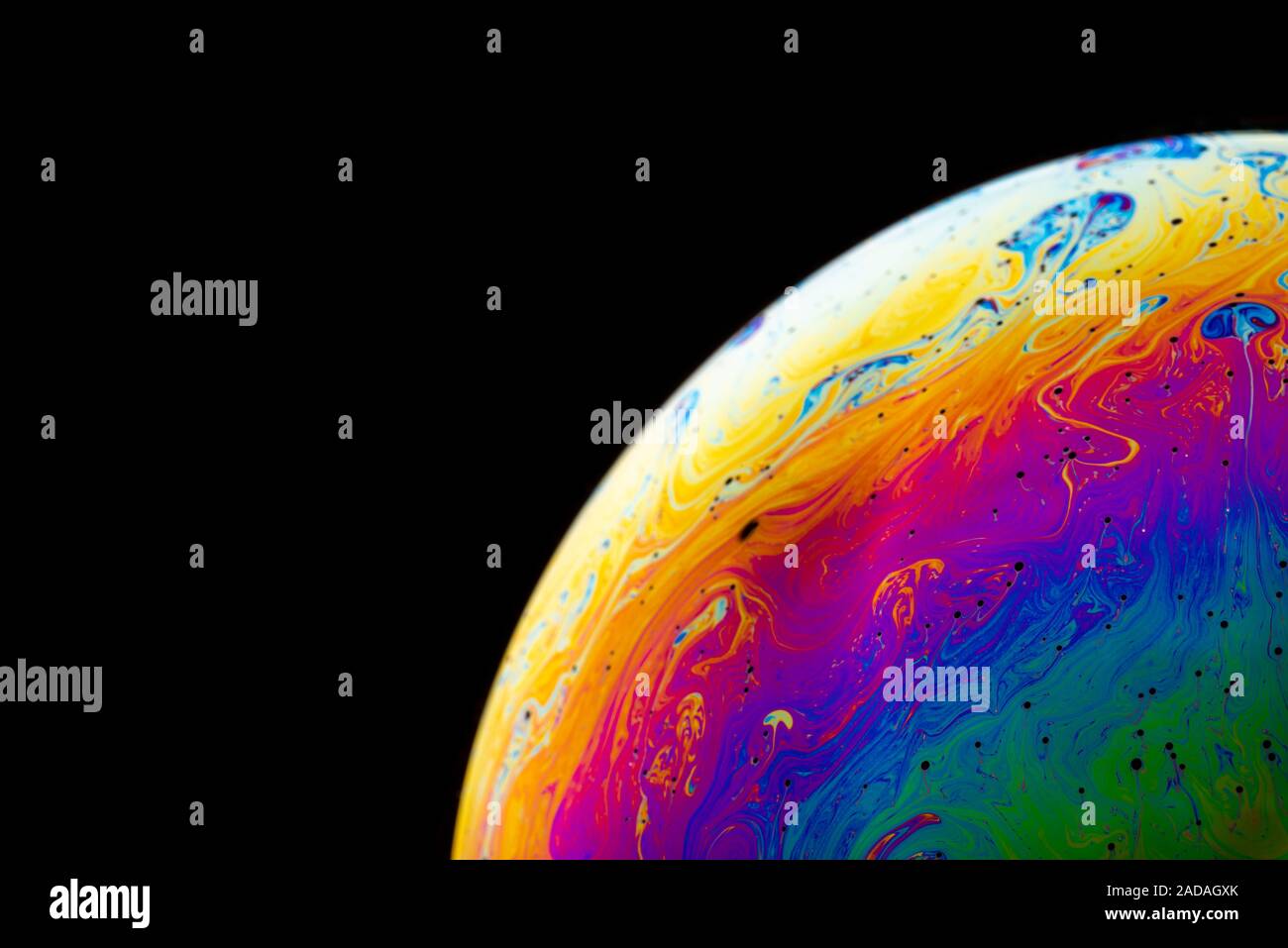 Rainbow soap bubble on a dark background. Stock Photo
