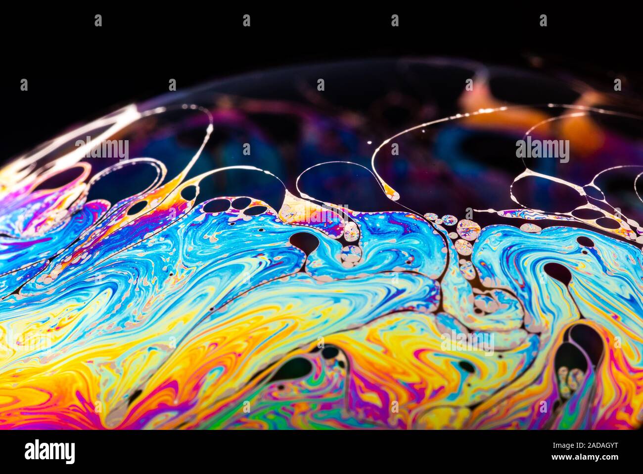 Rainbow soap bubble on a dark background. Stock Photo