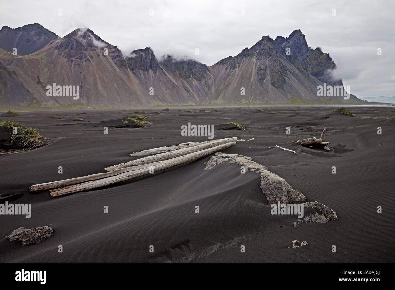 black lava beach with driftwood at Cape Stokksness with mountain Vestrahorn, Hornvik Bay, Iceland Stock Photo