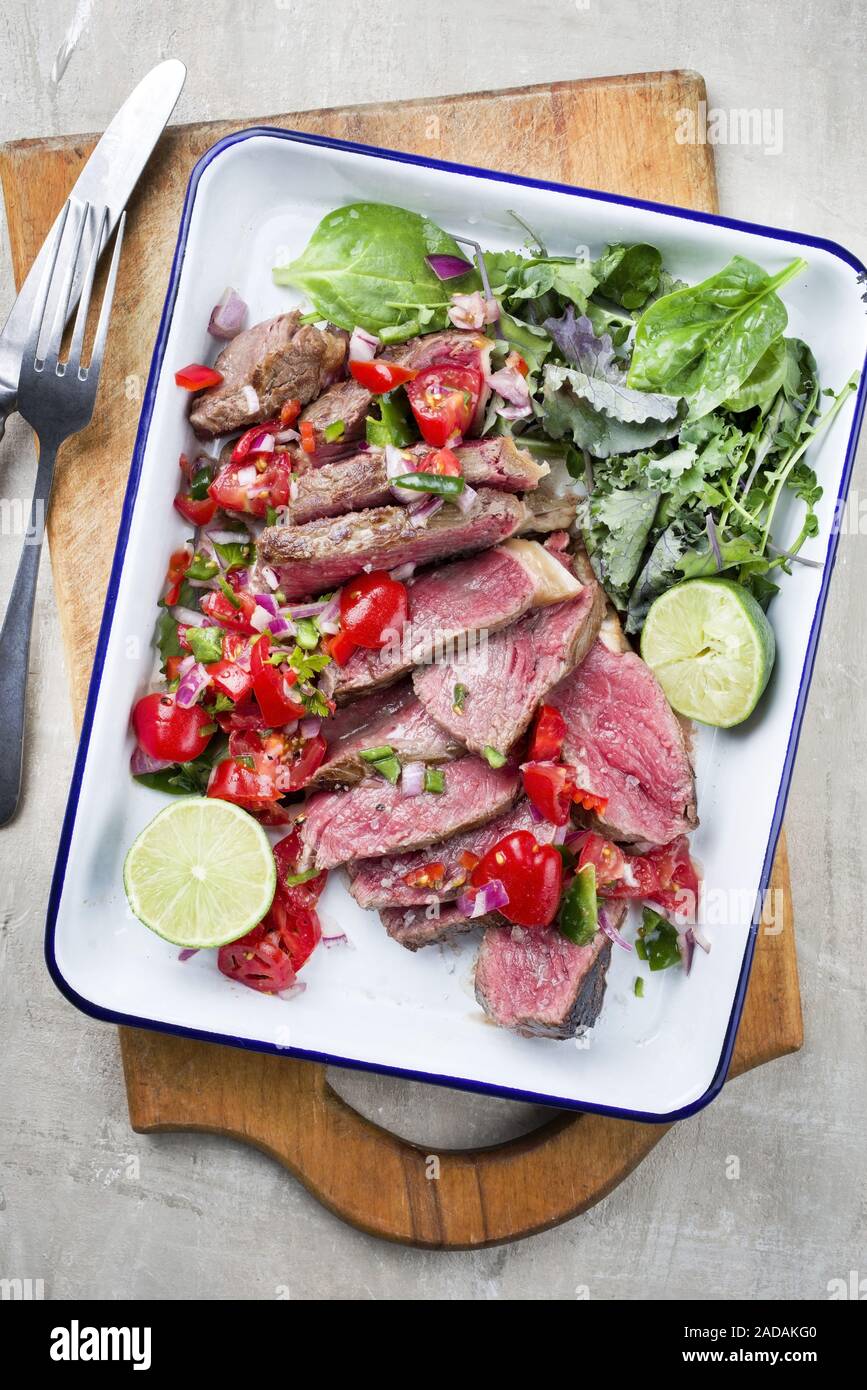 Traditional South American barbecue wagyu roast beef sliced with pico de gallo and salsa verde garnished with lettuce as top vie Stock Photo