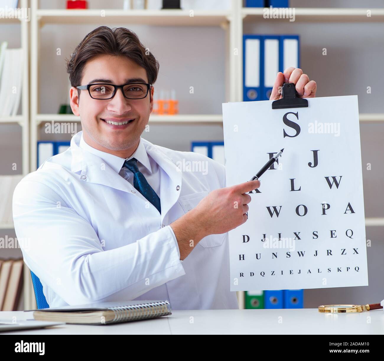 Doctor optician with letter chart conducting an eye test check Stock