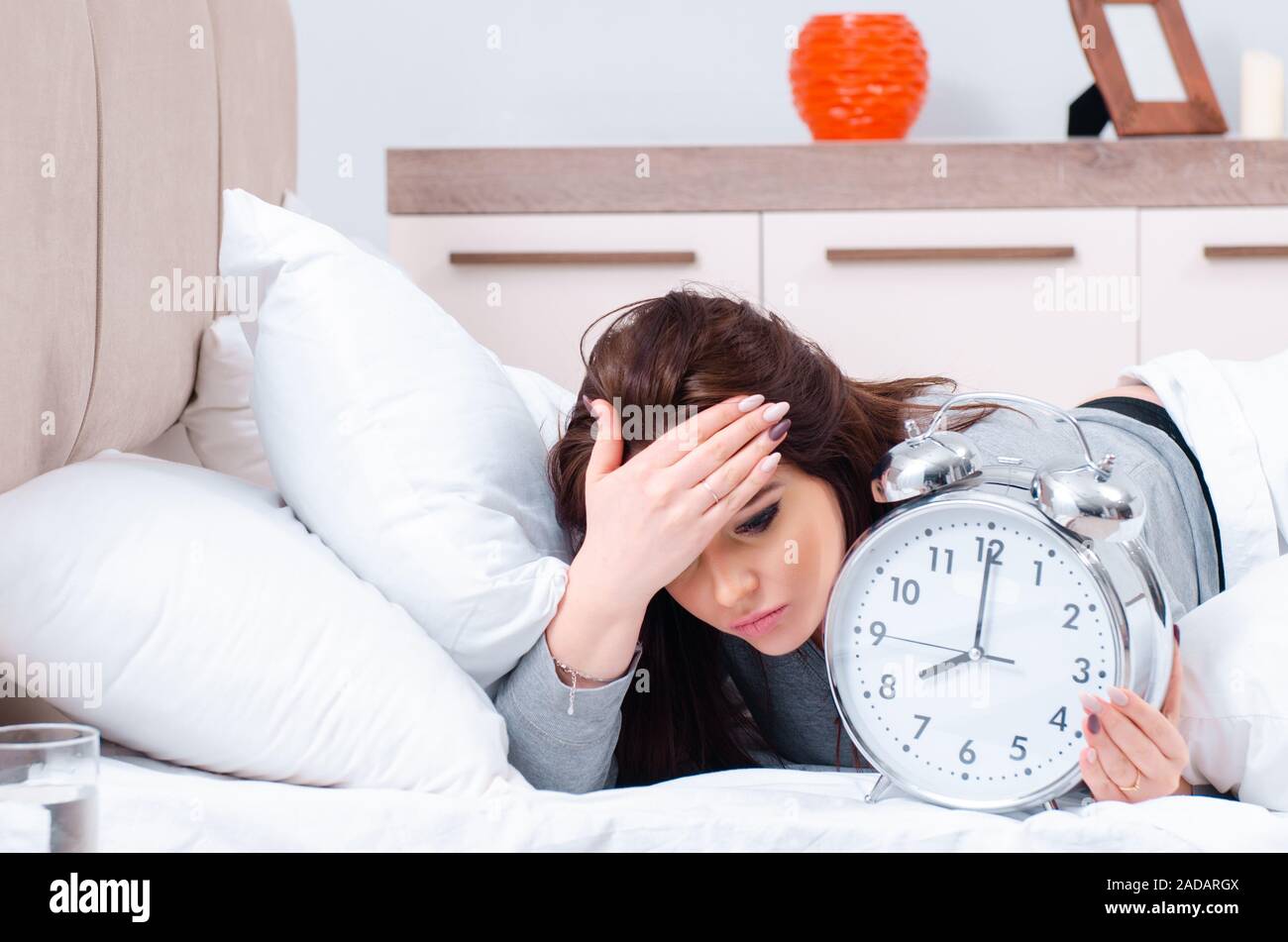 Young woman lying on the bed in time management concept Stock Photo Alamy