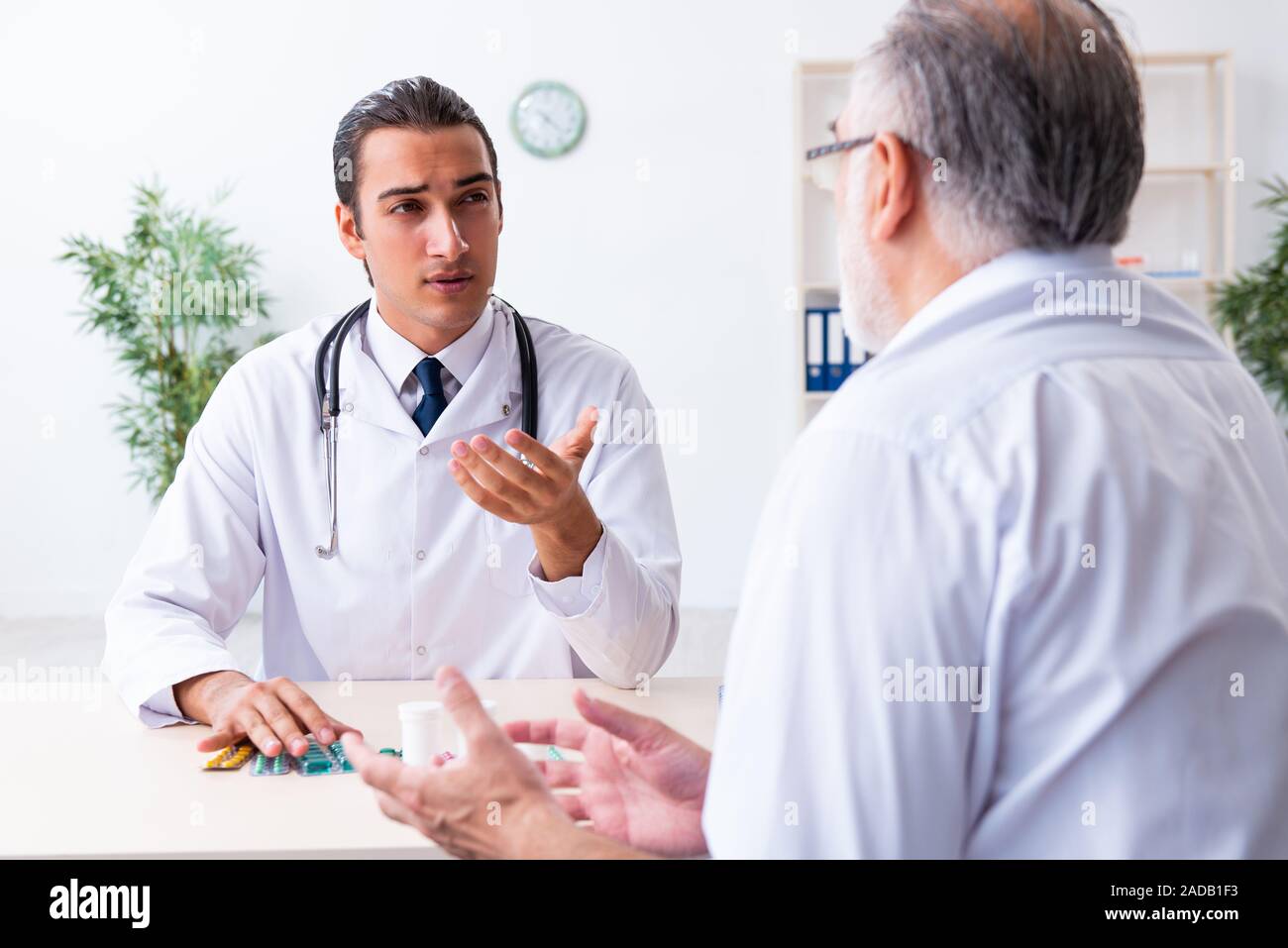 Old man visiting young male doctor Stock Photo