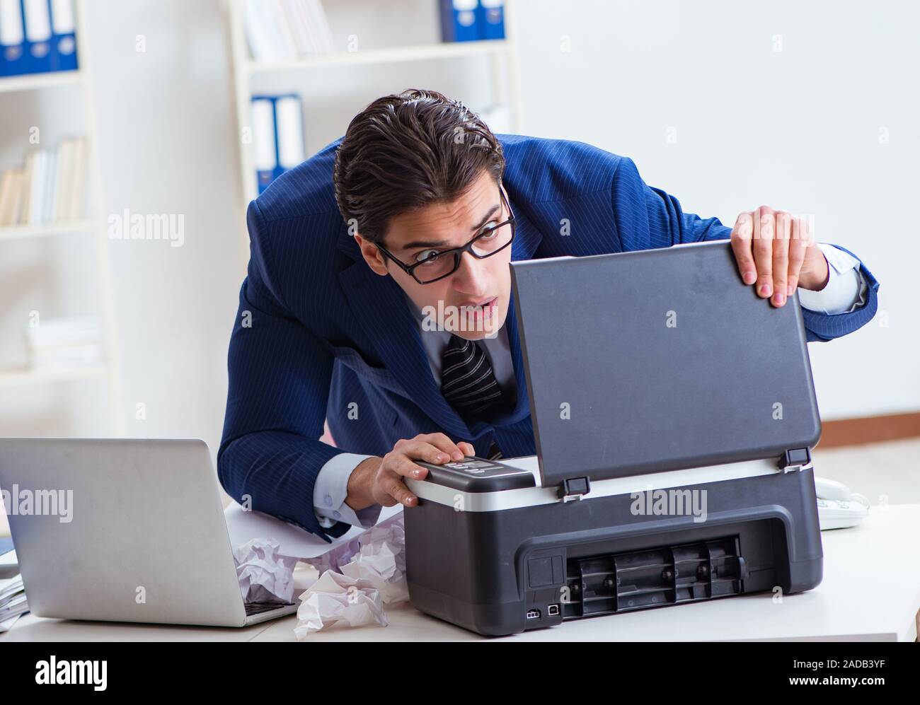 Businessman angry at copying machine jamming papers Stock Photo - Alamy