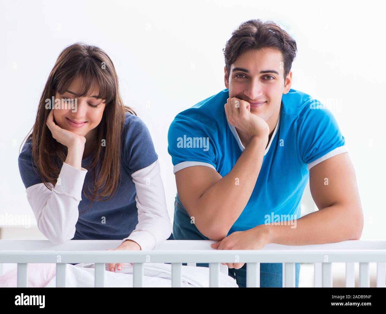 The happy young family at baby bed cot Stock Photo
