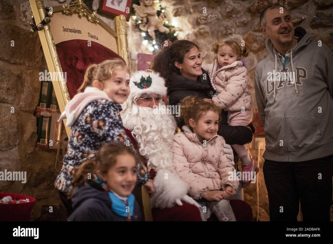 Jerusalem, Israel. 02nd Dec, 2019. A family has themselves photographed disguised as Santa Claus in his house with Issa Kassissieh (M). The former basketball player refers to several diplomas and certificates from Santa Claus schools in the USA and the Santa Claus World Congress in Copenhagen and is considered the only professional Santa Claus in the Middle East. (to dpa 'Santa Claus graduated from Jerusalem') Credit: Ilia Yefimovich/dpa/Alamy Live News Stock Photo