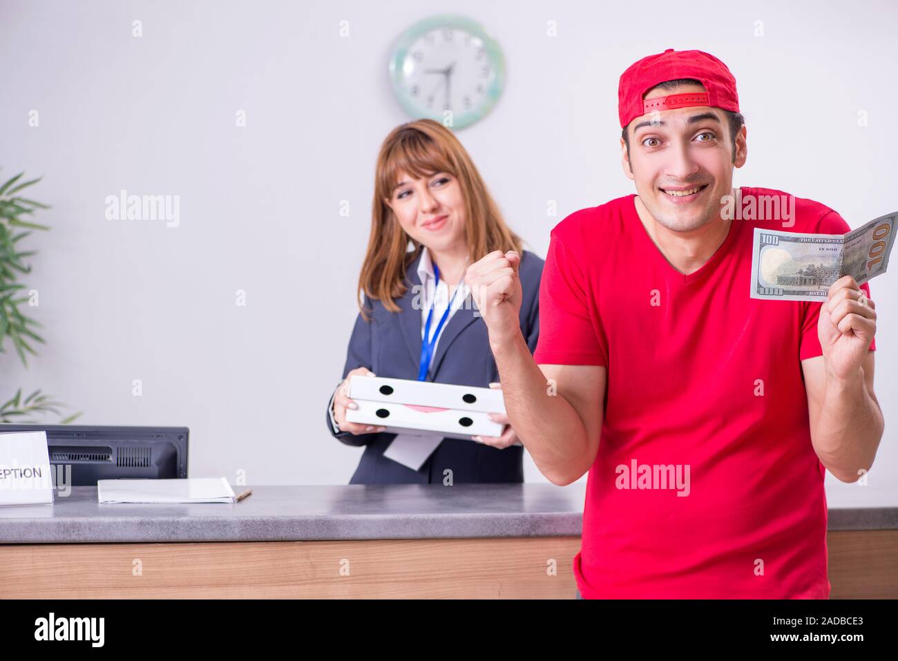 Young male courier delivering pizza to hotel's reception Stock Photo