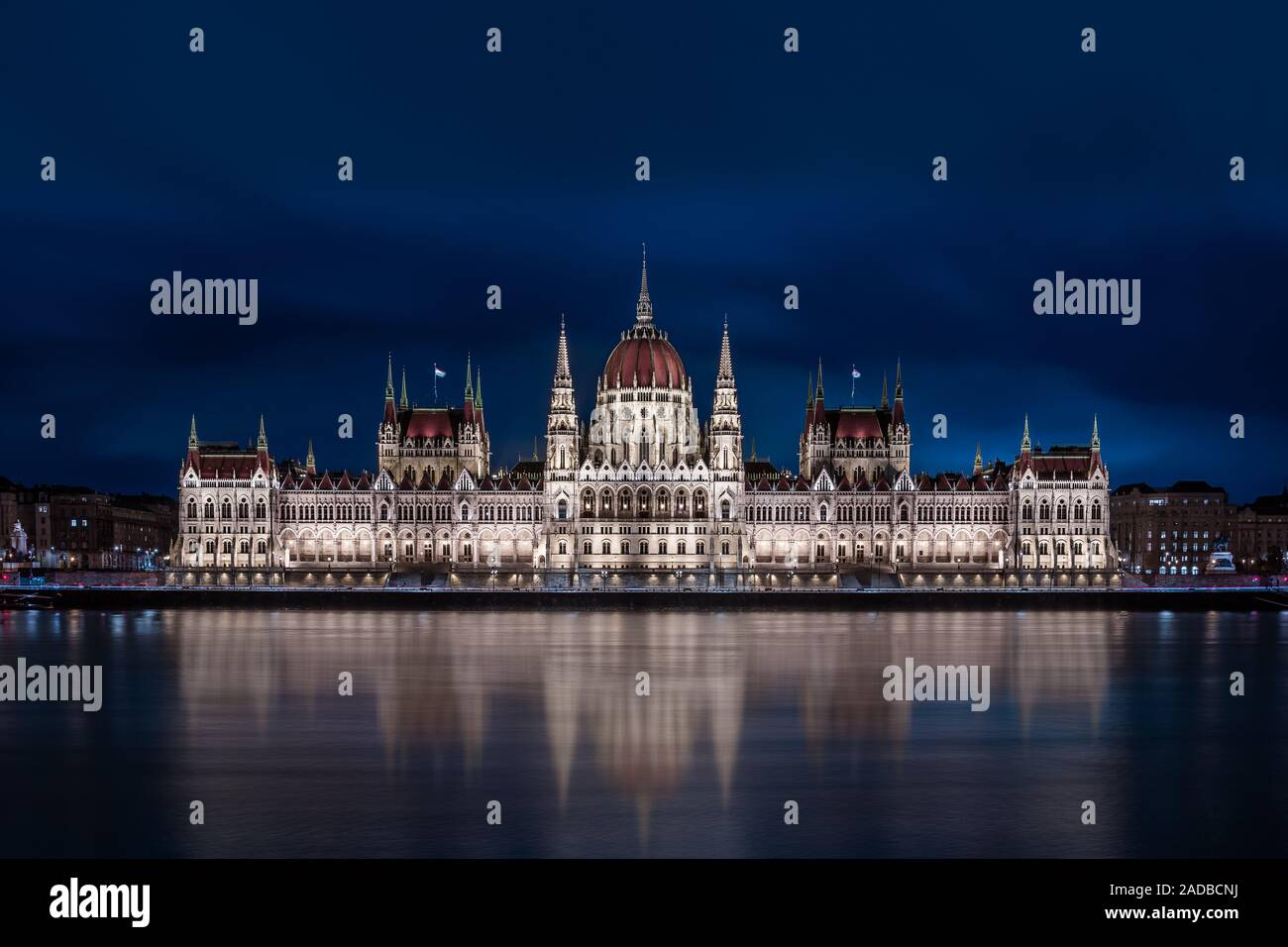 Budapest, Hungary - Illuminated Hungarian Parliament building with blue cloudy sky and reflection on River Danube at dusk Stock Photo