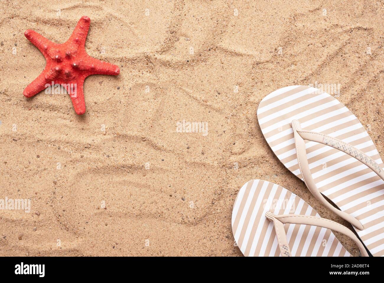 Sand beach, red starfish and flip flops background with copy space ...