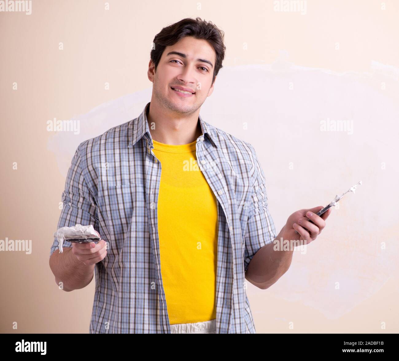 Young man applying plaster on wall at home Stock Photo