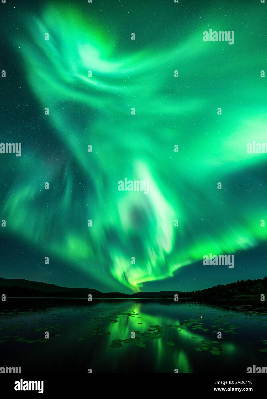 Aurora borealis over a lake, reflected in the water. This coloured ...