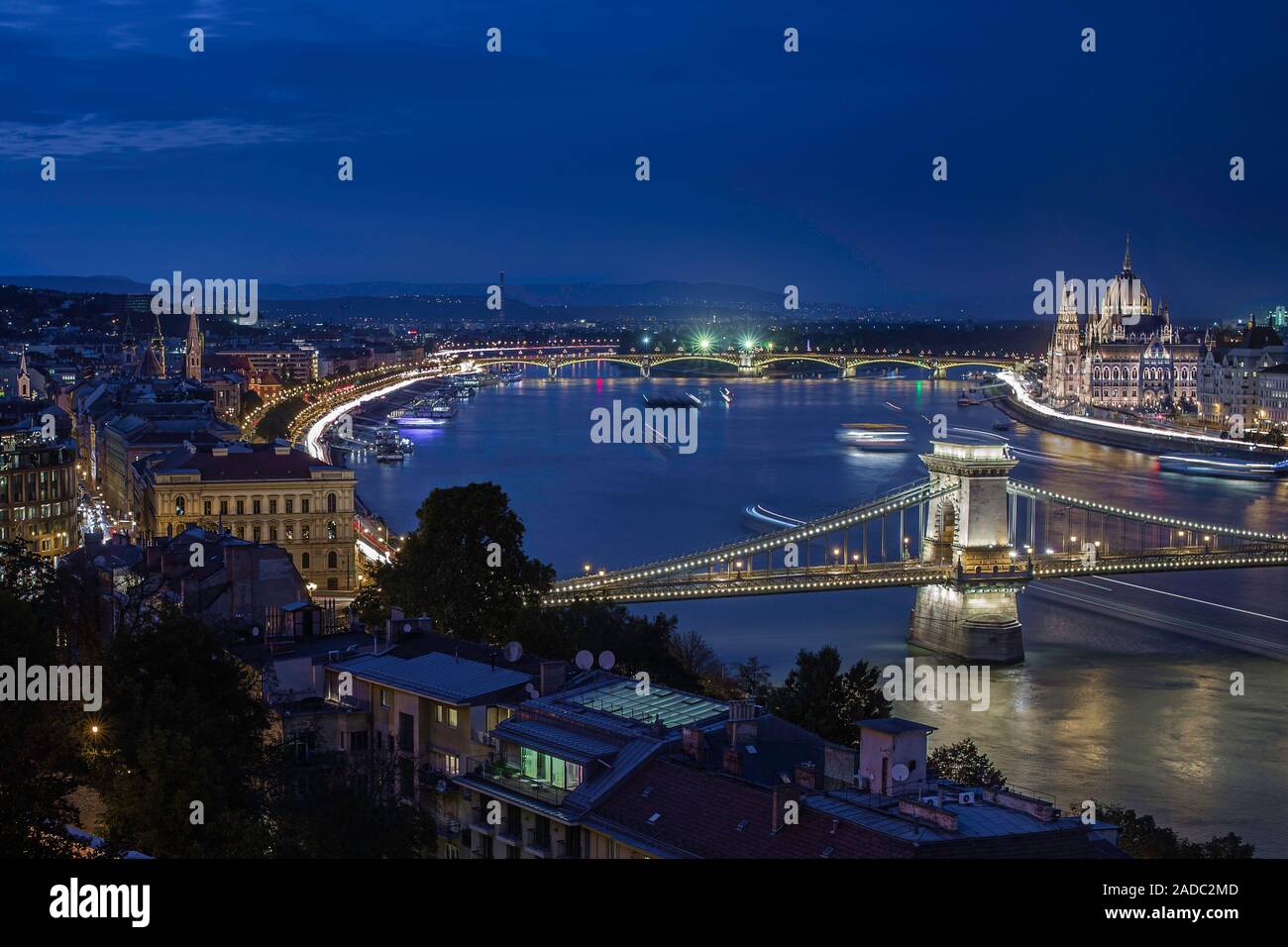 Budapest, Hungary - Illuminated Szechenyi Chain Bridge on a night photograph with Parliament of Hungary, moving ships on River Danube and clear dark b Stock Photo