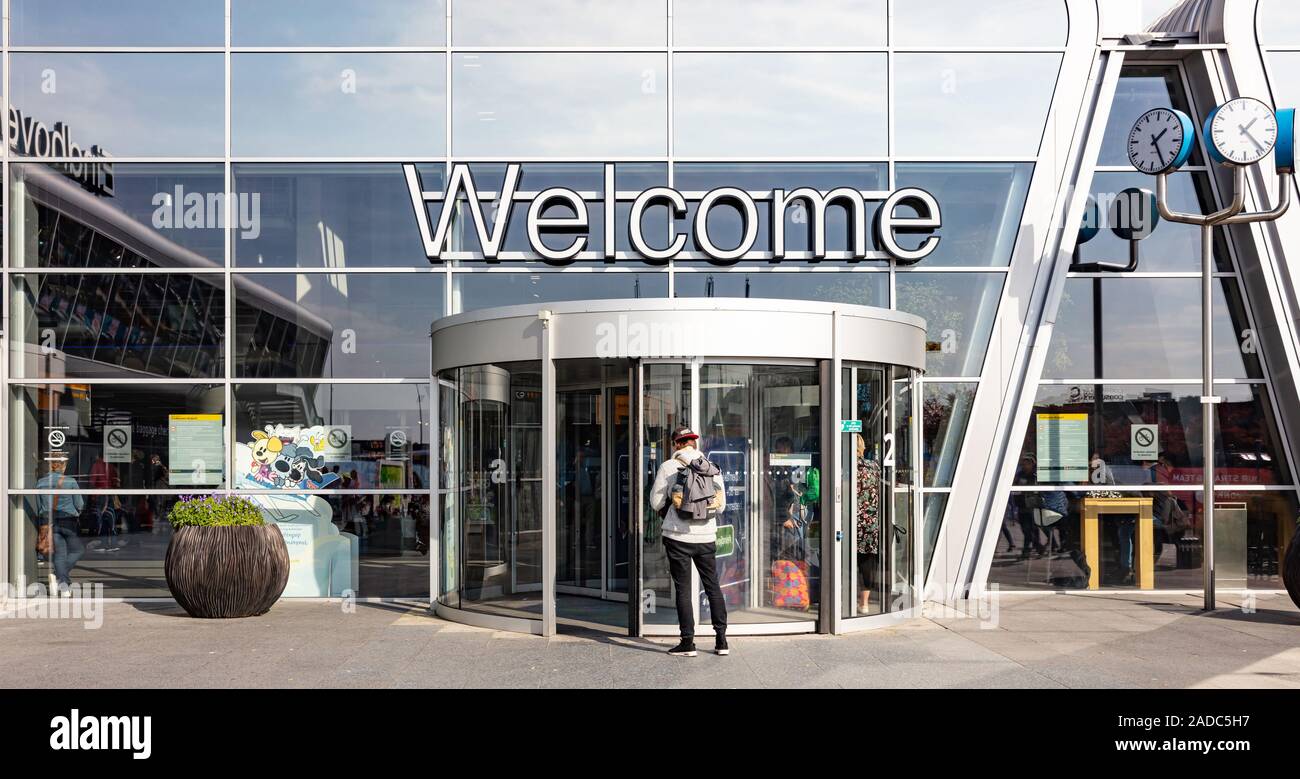 Eindhoven Netherlands. October 14, 2019. Welcome text sign at the Eindhoven airport terminal facade. Young man with backpack at the entrance, sunny au Stock Photo