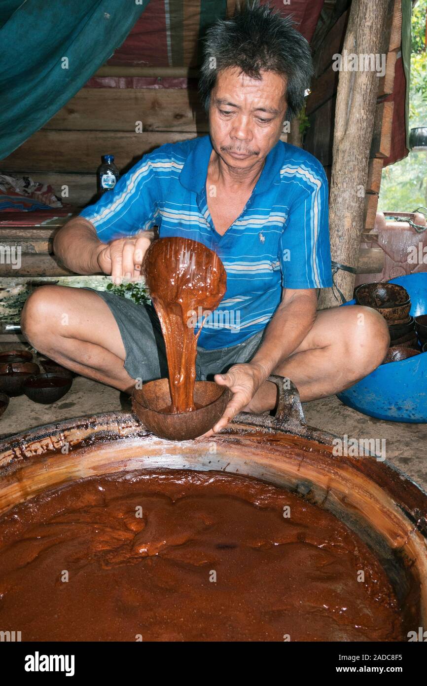 Preparing palm sugar. Man pouring a syrup prepared from the sap of palm trees. The sap is collected and boiled for hours until the sugars crystallise Stock Photo
