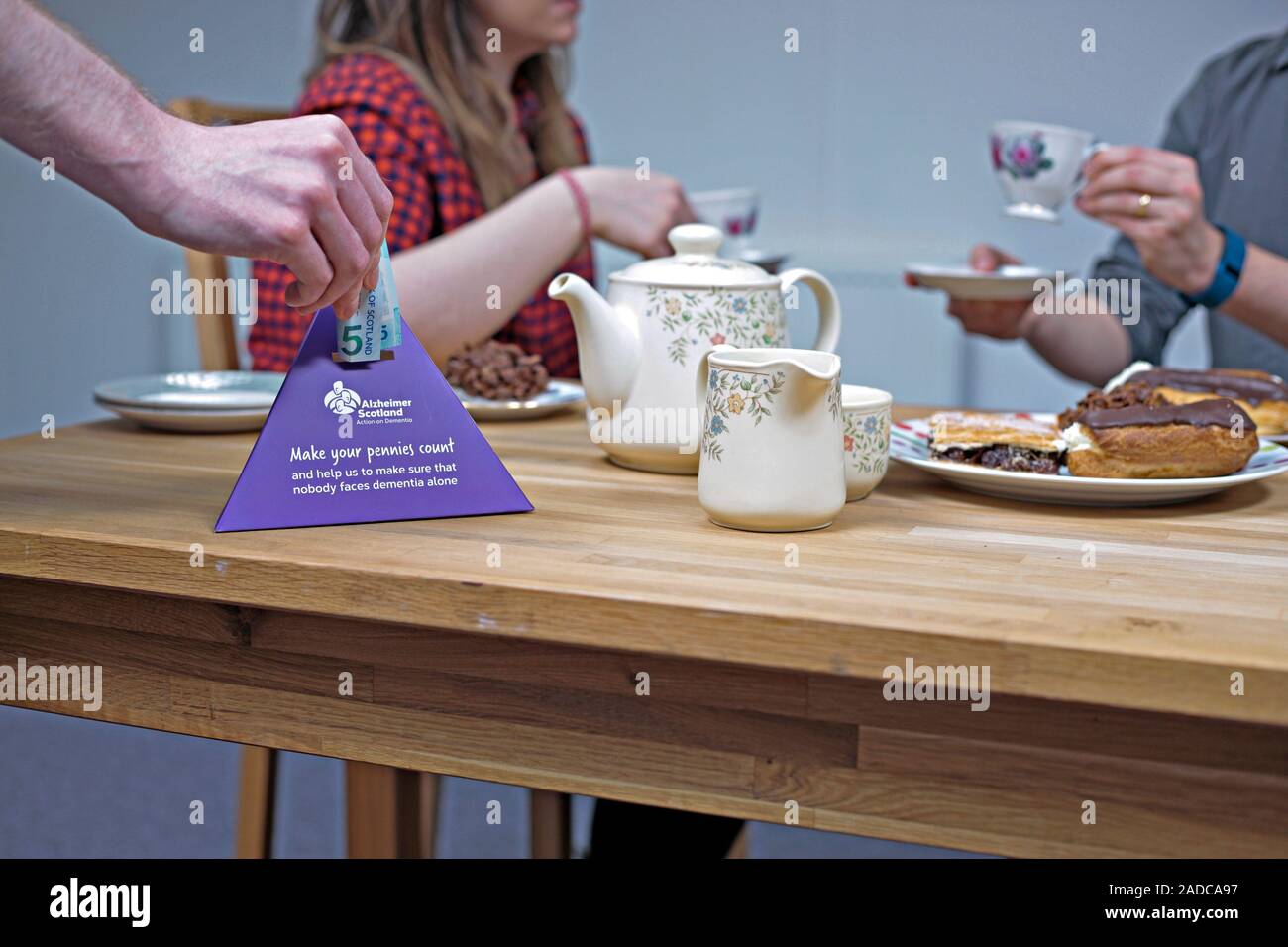 Dementia awareness fundraiser. Person making a cash donation at a 'Bake