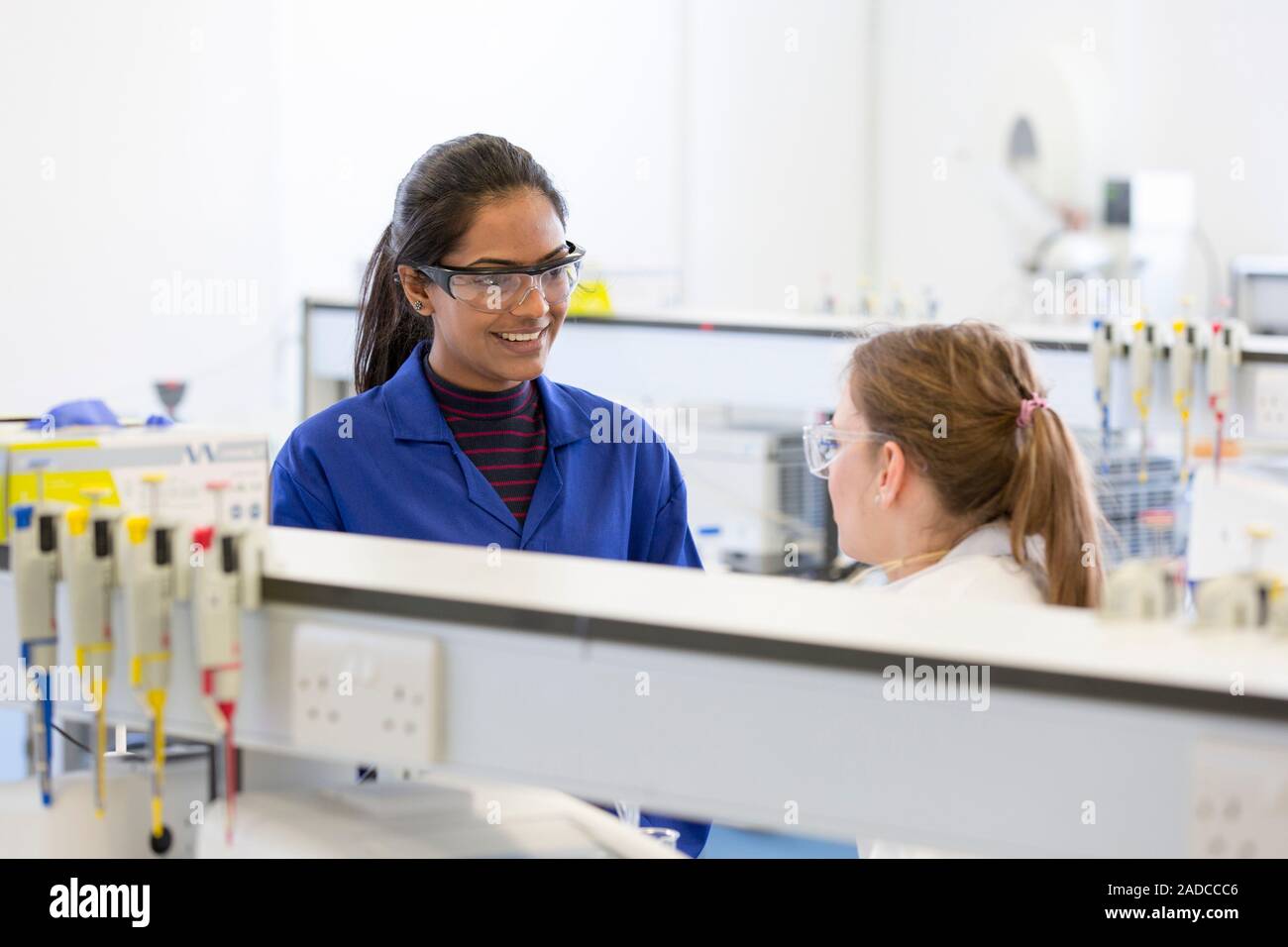 Lab supervisor or demonstrator (blue lab coat) talking with an