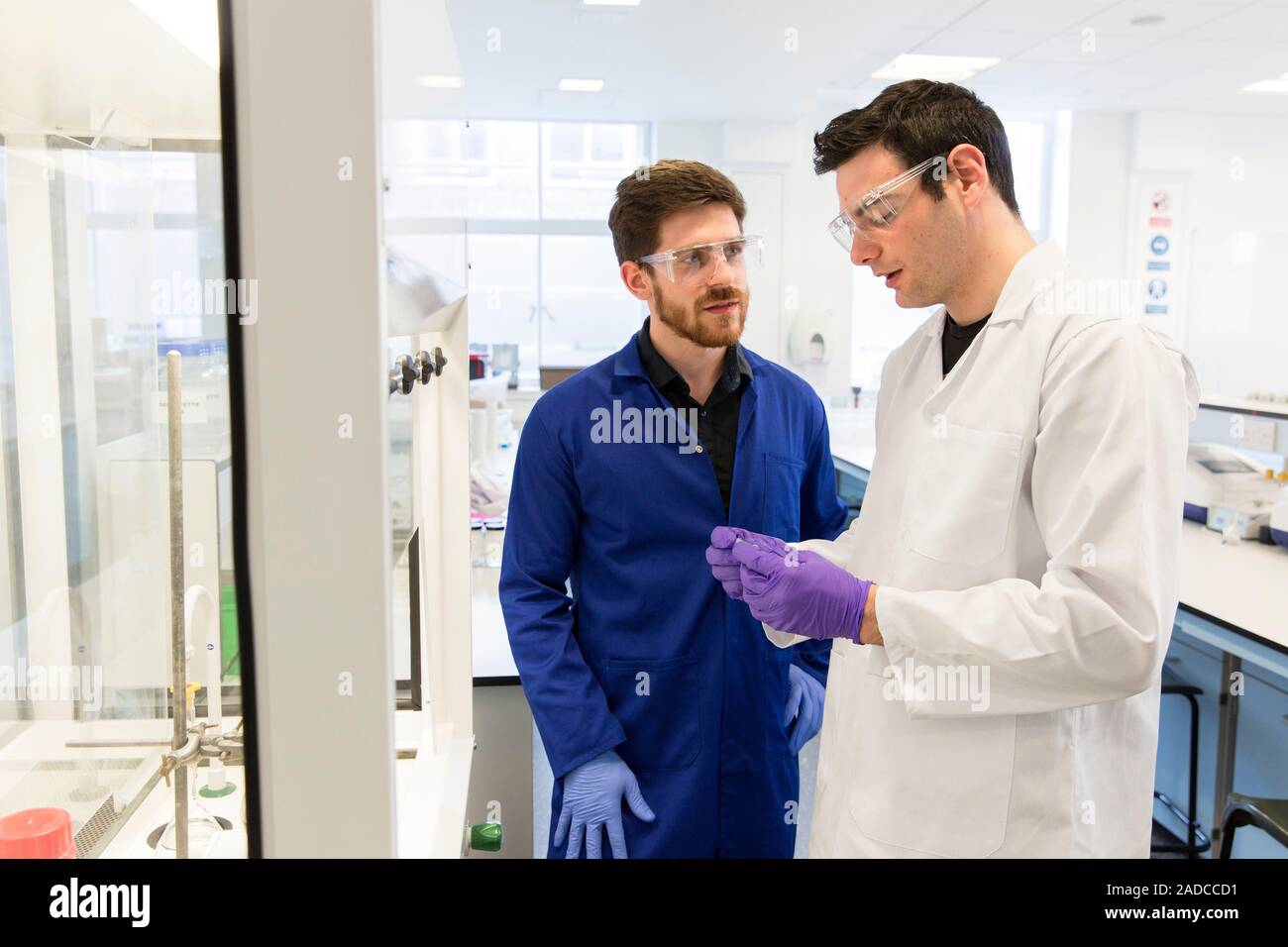Lab supervisor or demonstrator (blue lab coat) talking with an