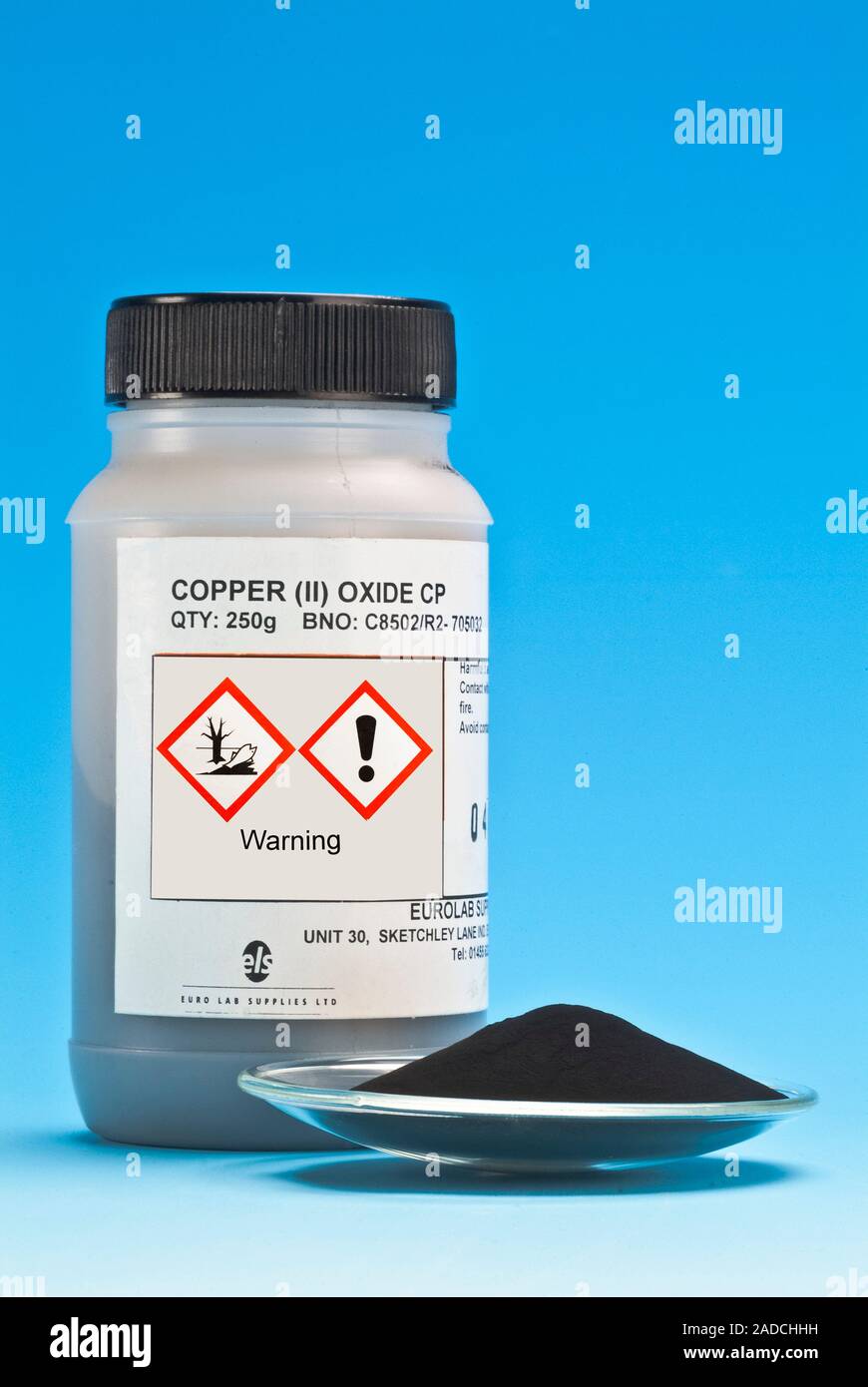 Copper (II) oxide (CuO) on a watch glass, with a container labelled