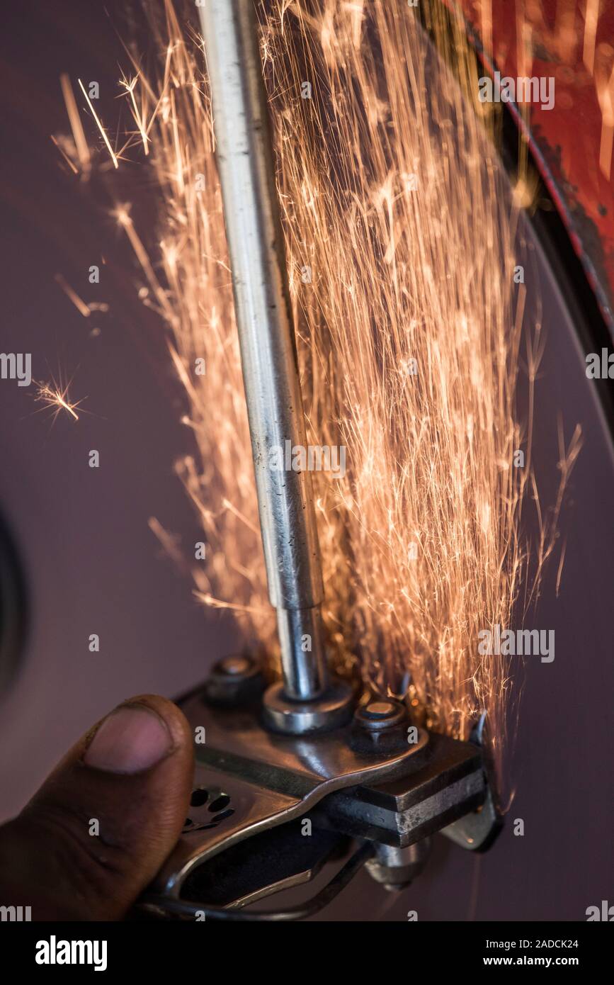Sheep shearer using a grindstone to sharpen the blade of an electric