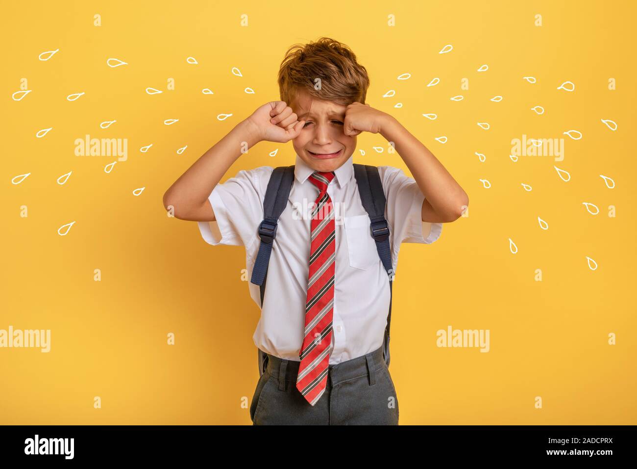 Child cries because does not want to go to school. Yellow background Stock Photo