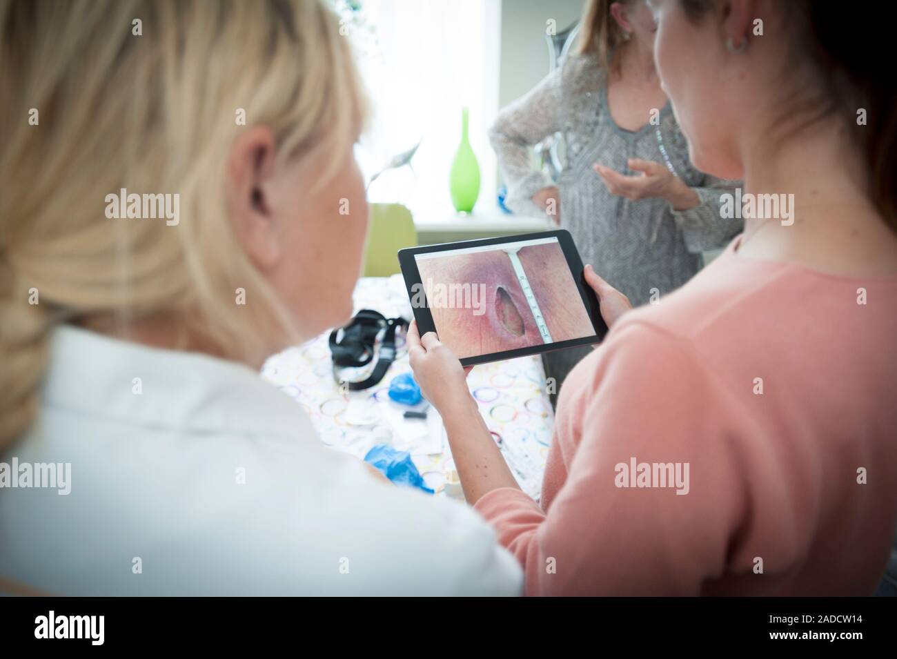 Home care nursing. Nurses using a tablet computer to evaluate a patient ...