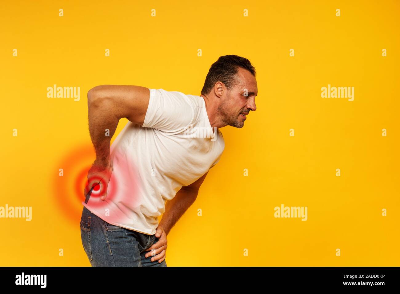 Aching man with back pain. Yellow background Stock Photo