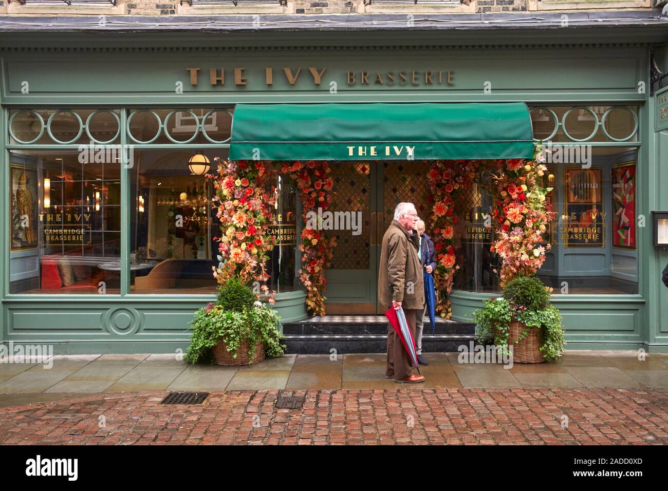 Older couple standing outside the Cambridge branch of The Ivy restaurant Stock Photo