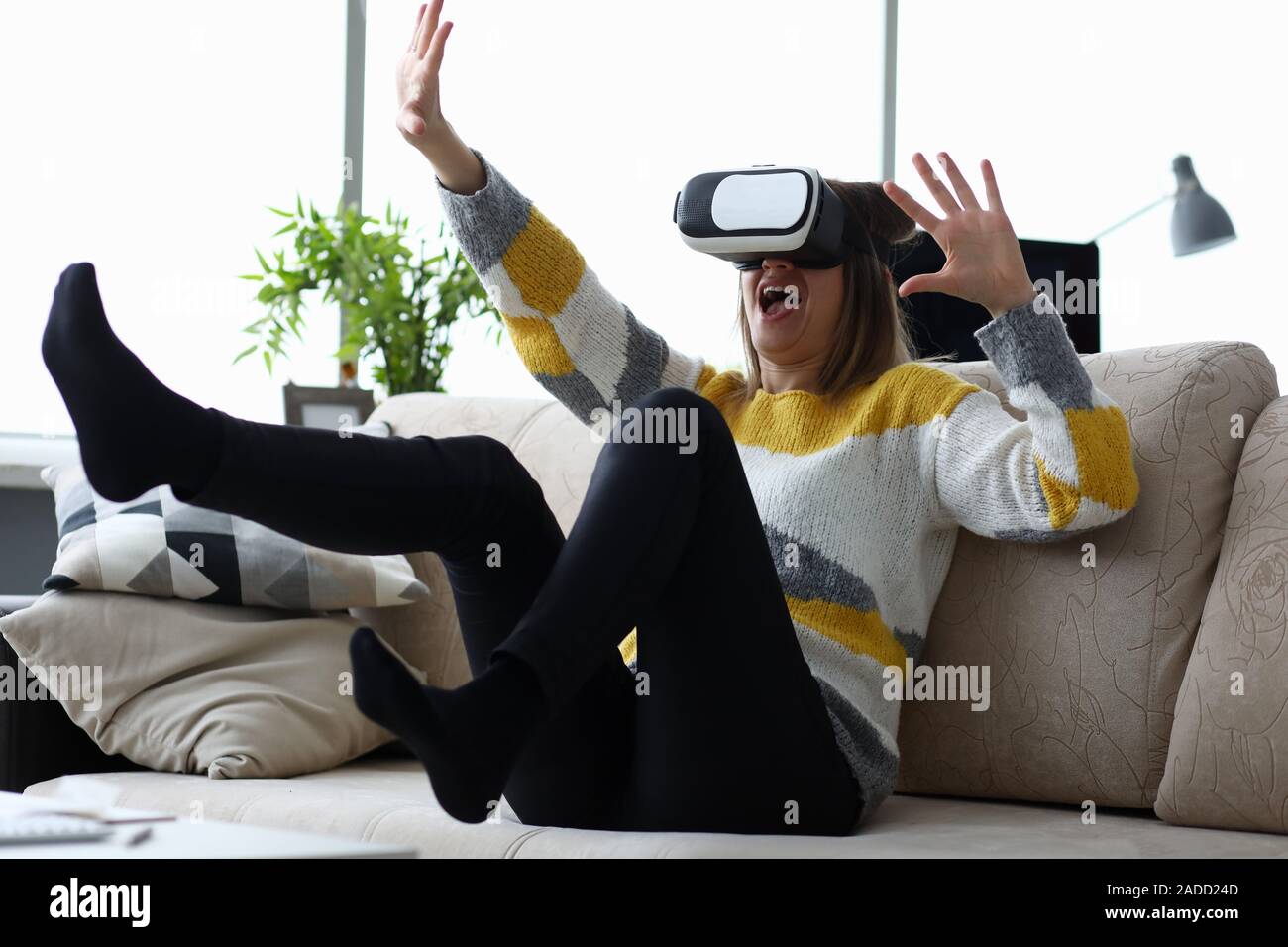 Woman sits at home on the couch uses virtual reality Stock Photo
