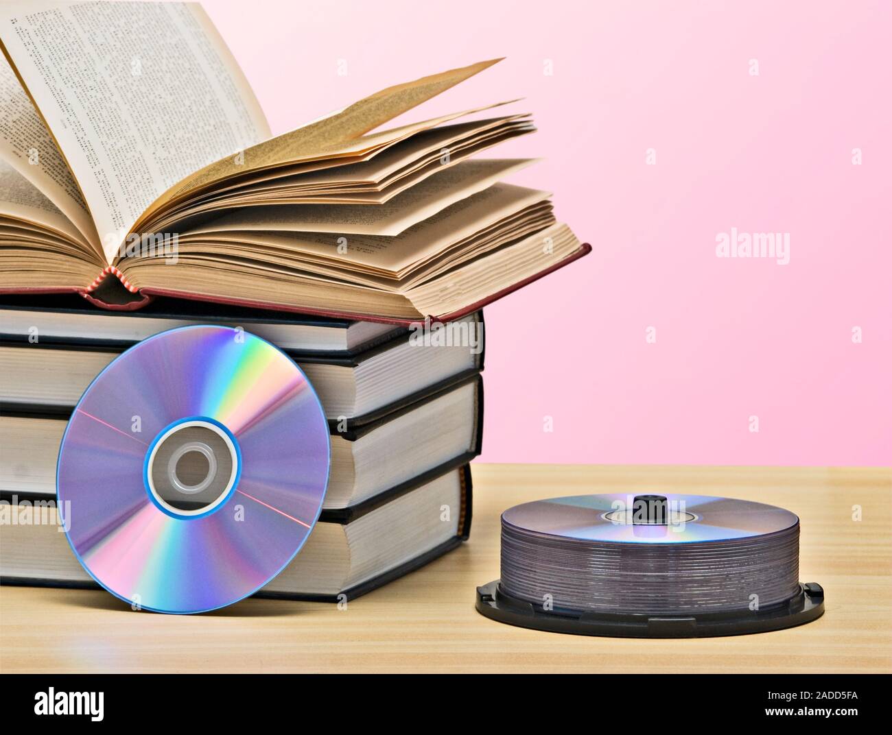 Pile of books  and DVD disk as symbols of old and new methods of information storage Stock Photo